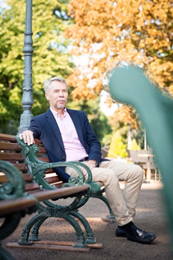 Timo Lindholm istuu puiston penkillä syksyisten puiden alla.