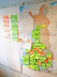 Kartta on Tuulin työhuoneen seinältä, ja auttaa havainnollistamaan hankkeiden määrää eri puolilla Suomea. Vihreät post-it -laput on käynnissä olevia hankkeita ja oranssit päättyneitä.