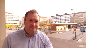 Jukka Hurrila, lyhyet hiukset,vaaleasininen paita. Taustalla näkyy kaupungin tori.
