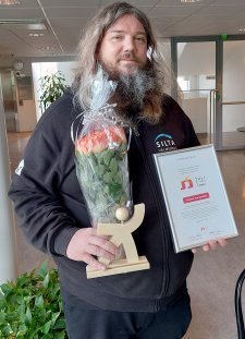 Parrakas, pitkätukkainen Kimmo Kumlander Tulisielu-kunniakirjan ja ruusukimpun kanssa.