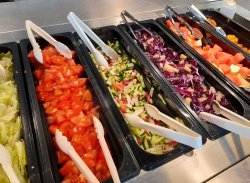 Lähikuva salaattipöydästä, jossa näkyy viittä erilaista salaattia ja ottimia.